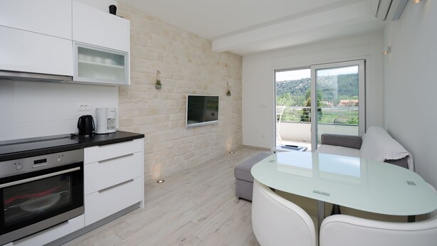 Eine moderne Küche mit weißen Schränken, einem eingebauten Backofen und einem großen Fenster mit Blick auf Grünflächen und Gebäude.