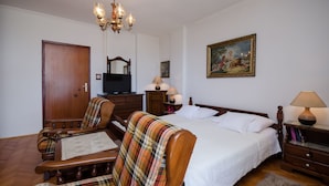 A bedroom with a bed, a wooden chair, a television, a lamp, and a painting on the wall. - Apartments Zeljko (Lovran)