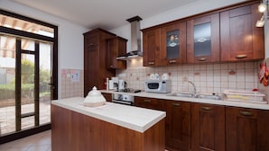 A modern kitchen with wooden cabinets, a central island, a microwave, and a stove. - Apartments Zeljko (Lovran)