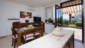 A modern kitchen with a dining table, chairs, a TV, and a view of the outdoors. - Apartments Zeljko (Lovran)