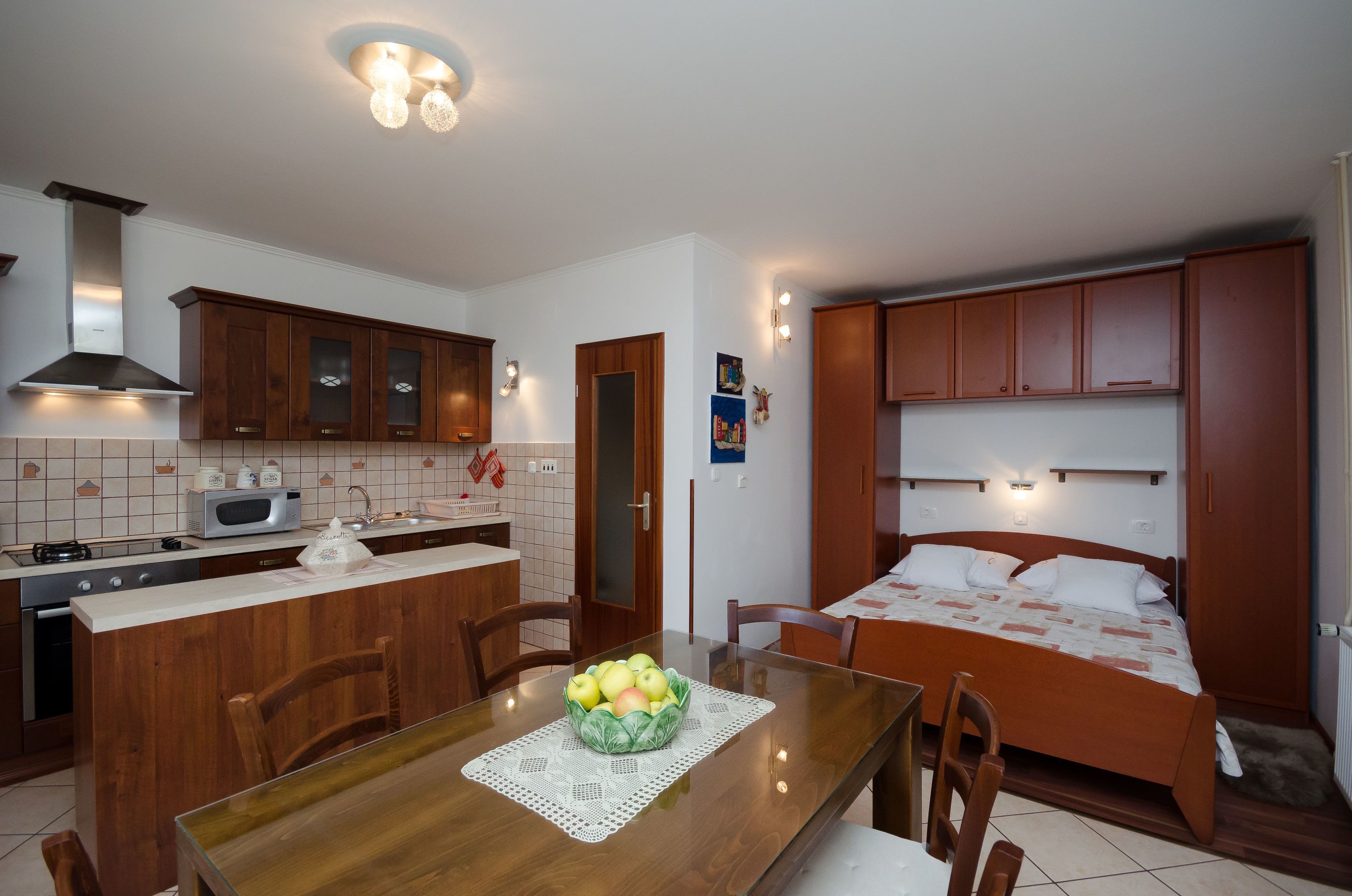 A compact kitchen with wooden cabinets, a microwave, and a dining area with a table and chairs.