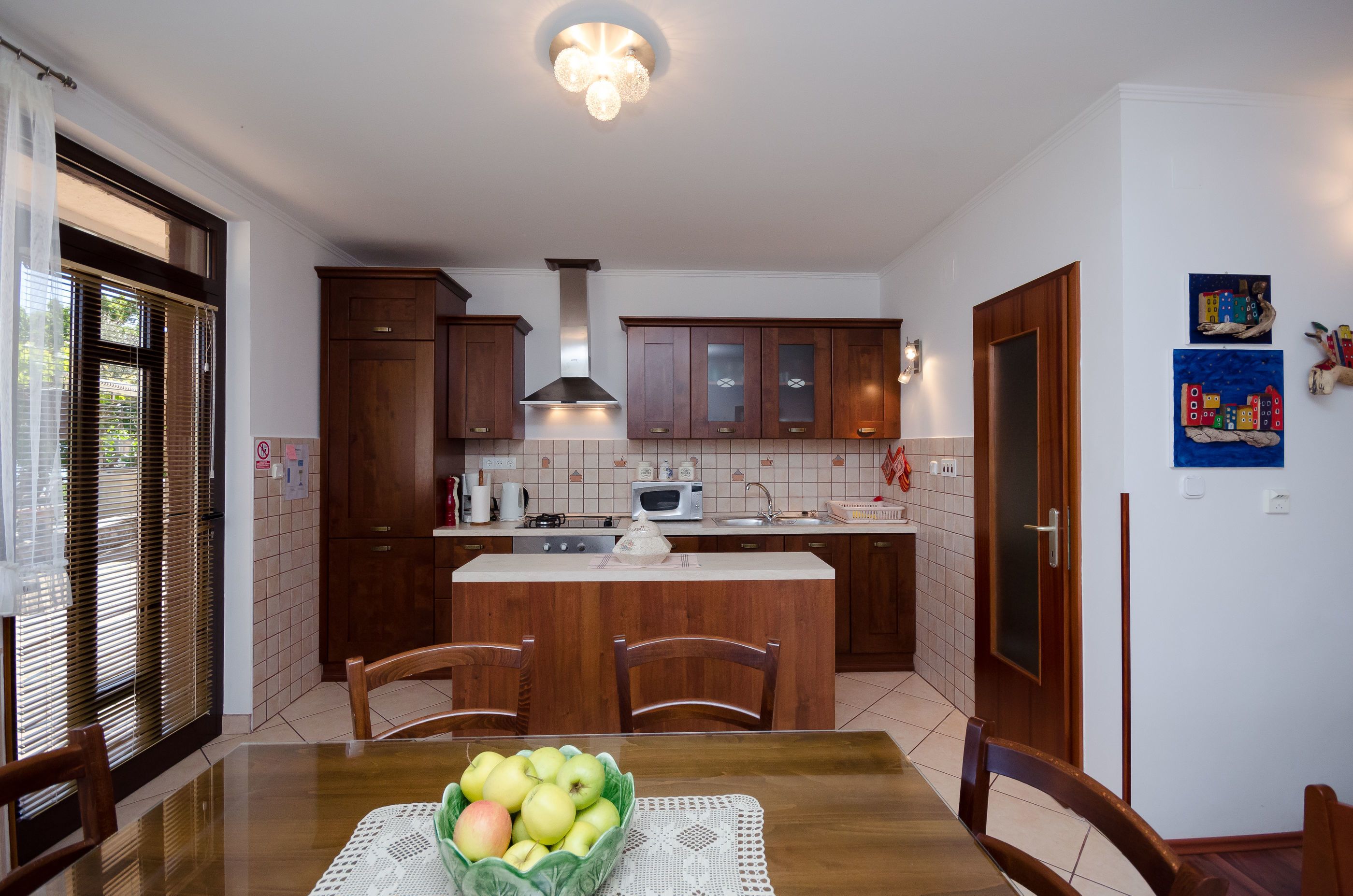 A kitchen with wooden cabinets, a central island, and a dining table with chairs.
