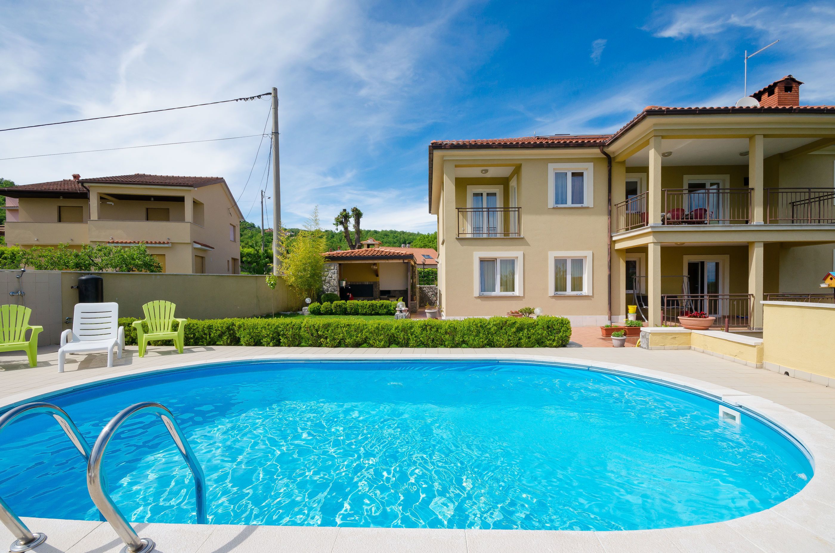Una piscina con agua cristalina azul, rodeada de una zona con sillas y un edificio con balcones.