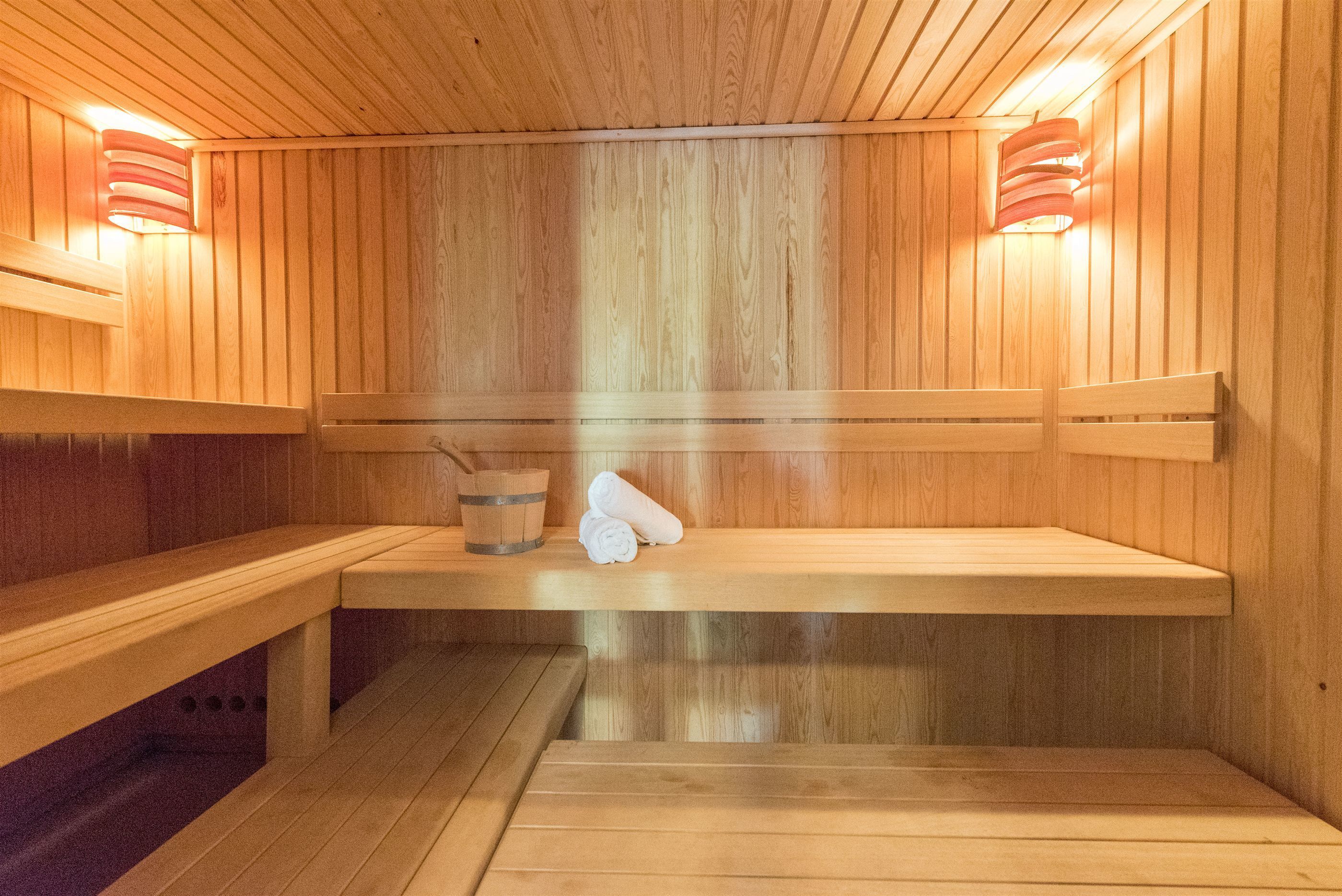 A wooden sauna with benches and benches, a wooden wall, and a wooden floor.