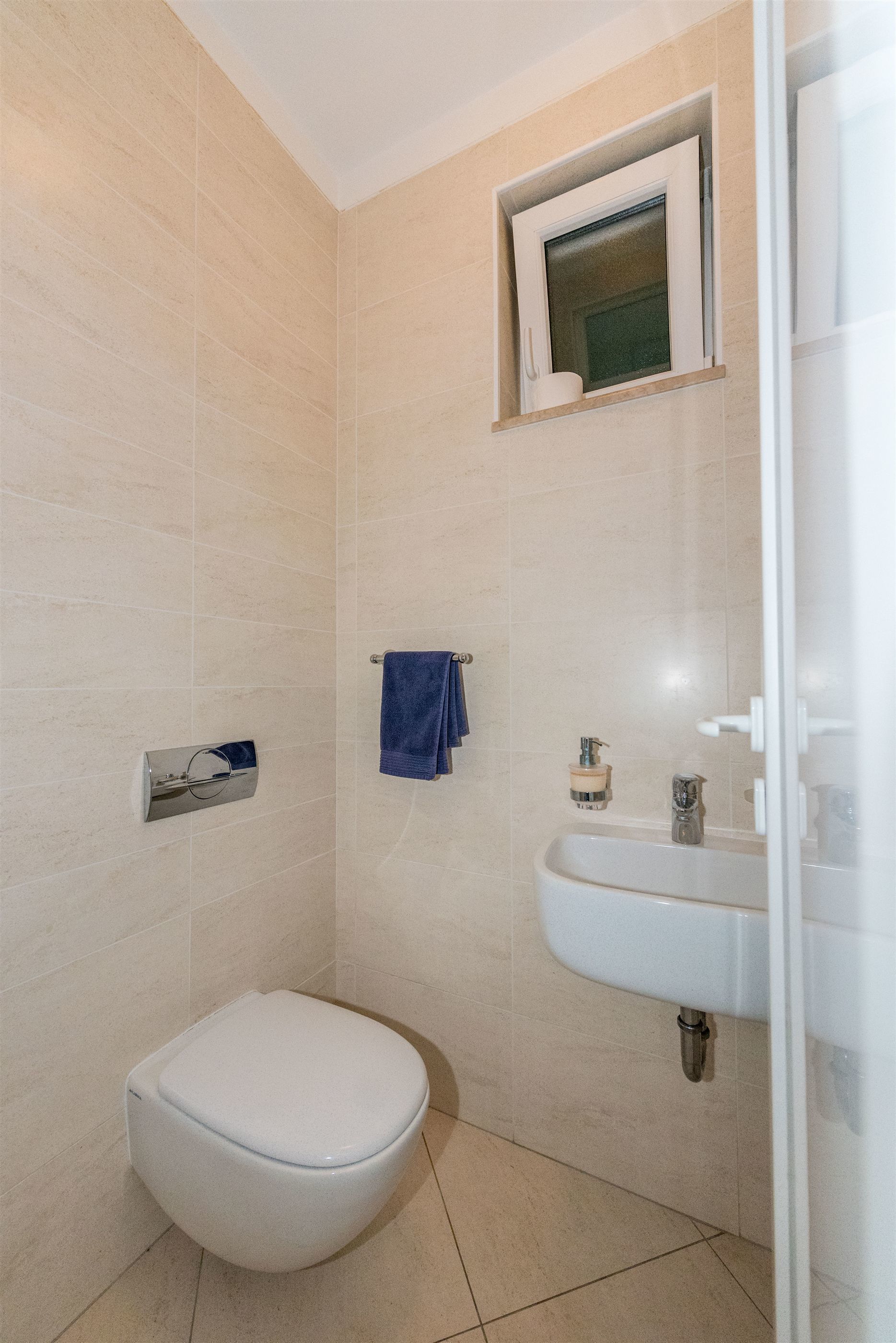 Une salle de bain avec des toilettes, un lavabo et une petite fenêtre.