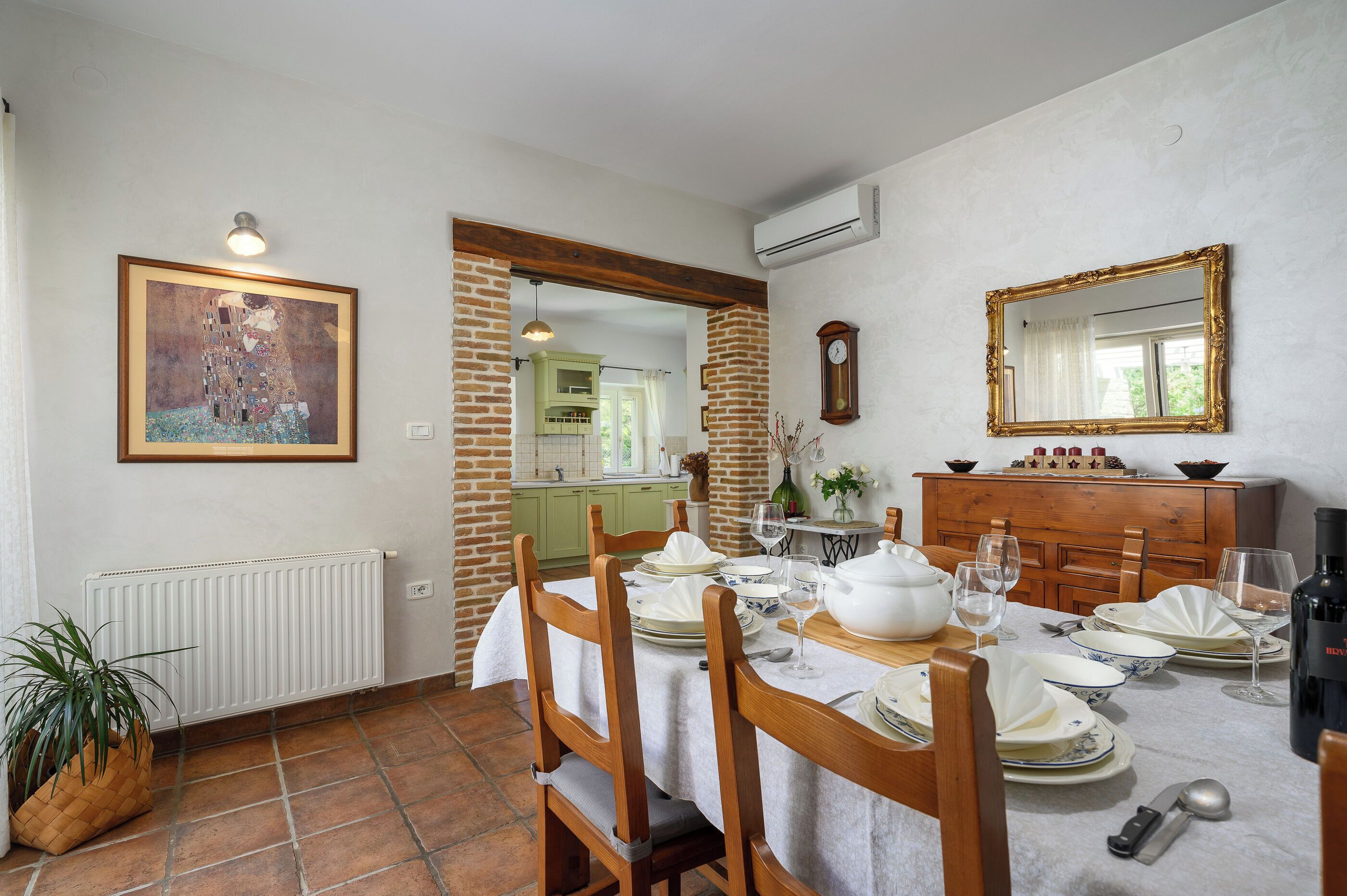 Un comedor con una mesa dispuesta para cuatro personas, un reloj y un espejo en la pared.