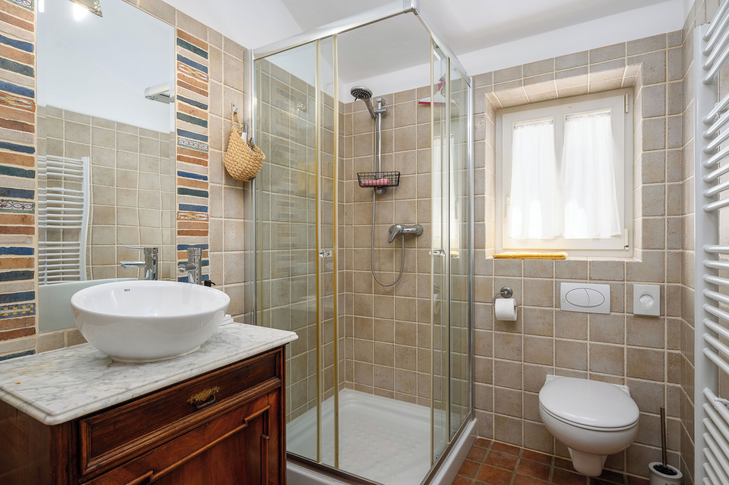 Een badkamer met een douchecabine van glas, een witte wastafel en een toilet.