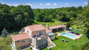 Une maison à deux étages avec une piscine, une façade en pierre et un jardin.