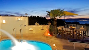 A rooftop pool area with a hot tub, outdoor seating, and a view of the ocean at dusk. - Villa Serena (Mirca)