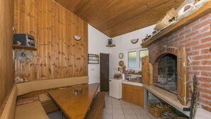Una cocina rústica con chimenea de ladrillo, paredes de madera y un banco.