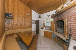 Una cocina rústica con chimenea de ladrillo, paredes de madera y un banco.