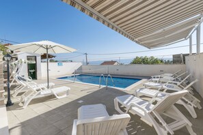 A rooftop pool area with white lounge chairs and a swimming pool. - Villa Leo (Jesenice)