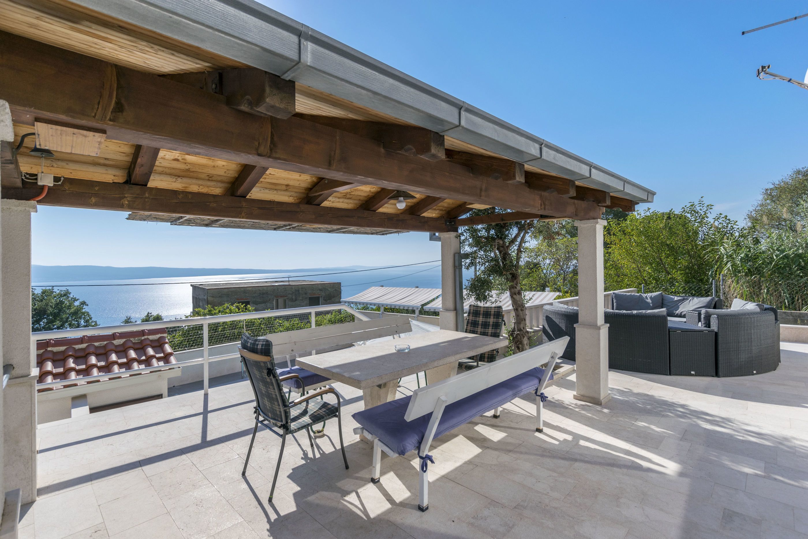 A covered outdoor area with a table and chairs, a bench, and a sofa.