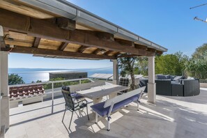 A covered outdoor area with a table and chairs, a bench, and a sofa. - Villa Leo (Jesenice)