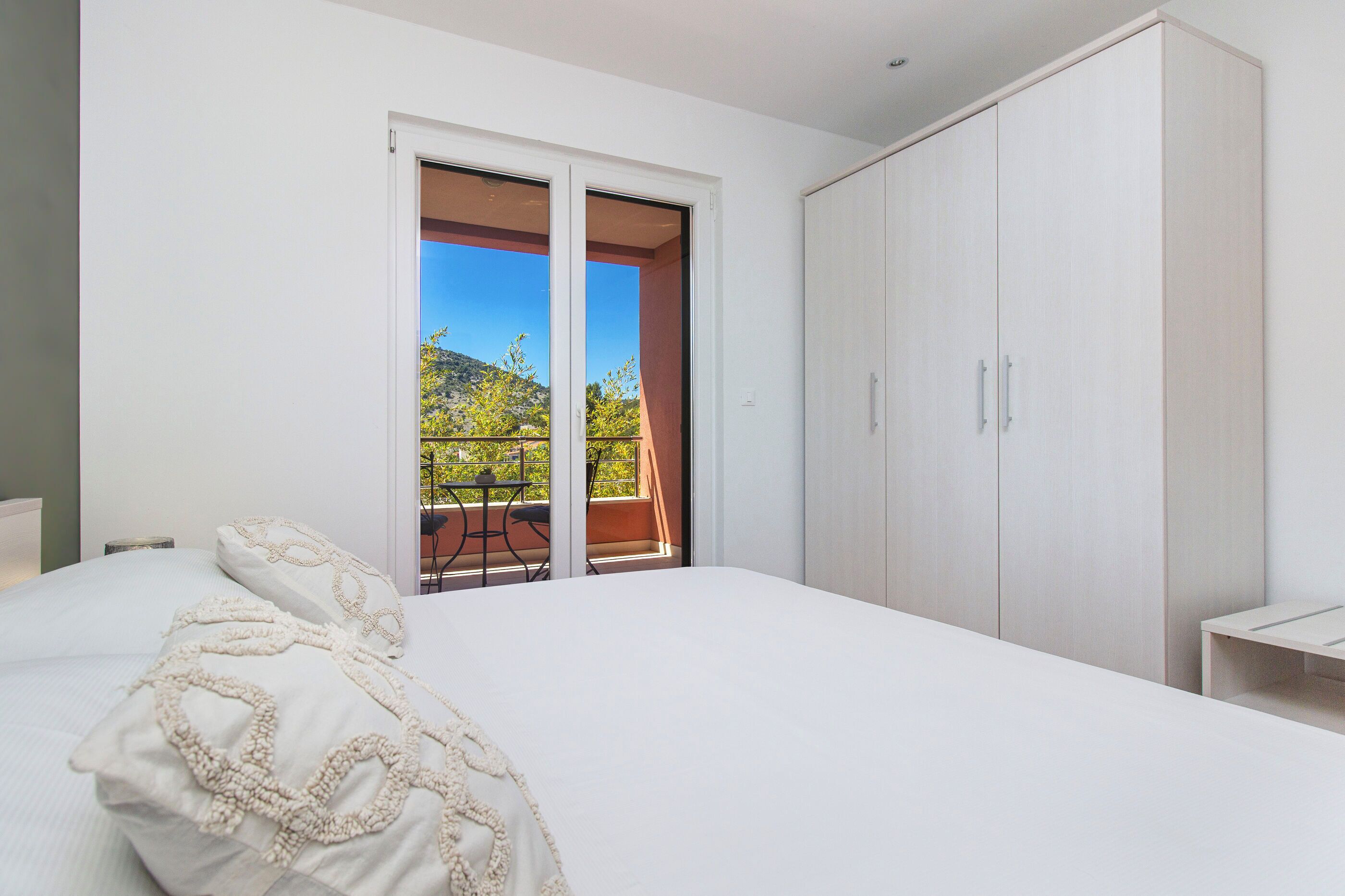 Una camera da letto con un letto grande, un armadio e un balcone con tavolo e sedie.