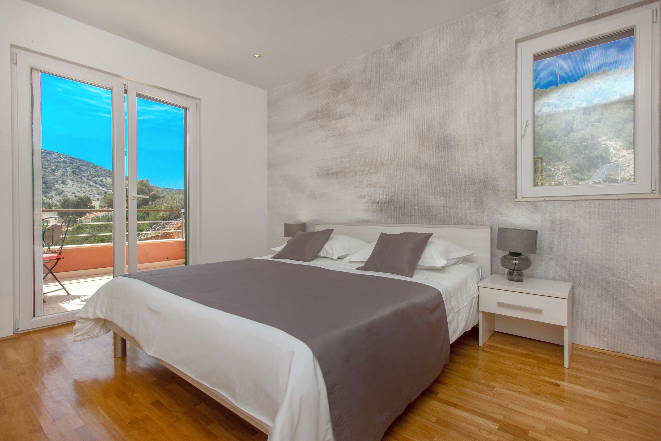 Une chambre à coucher avec un lit, une table de chevet et une vue sur un balcon.