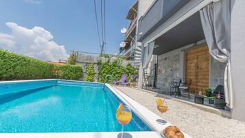 Una piscina con bebidas y un croissant en el borde.