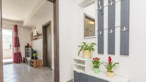 Ein Flur mit Fernseher, Topfpflanzen und einem Kleiderständer.