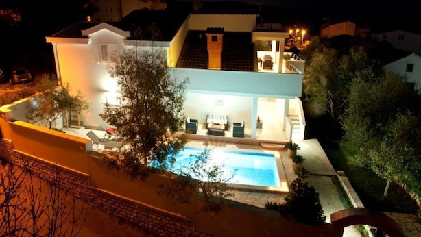A two-story house with a swimming pool, a covered patio, and a well-lit exterior at night. - Villa Doris (Okrug Gornji)