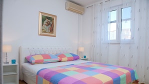 A bedroom with a bed, two bedside tables, a nightstand, a window, and a painting on the wall. - Villa Doris (Okrug Gornji)