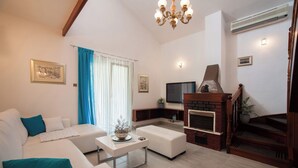 A modern living room with a white sofa, a coffee table, and a fireplace. - Villa Doris (Okrug Gornji)
