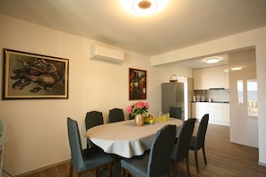 Un comedor con una mesa redonda, sillas, un florero con flores y obras de arte en las paredes.