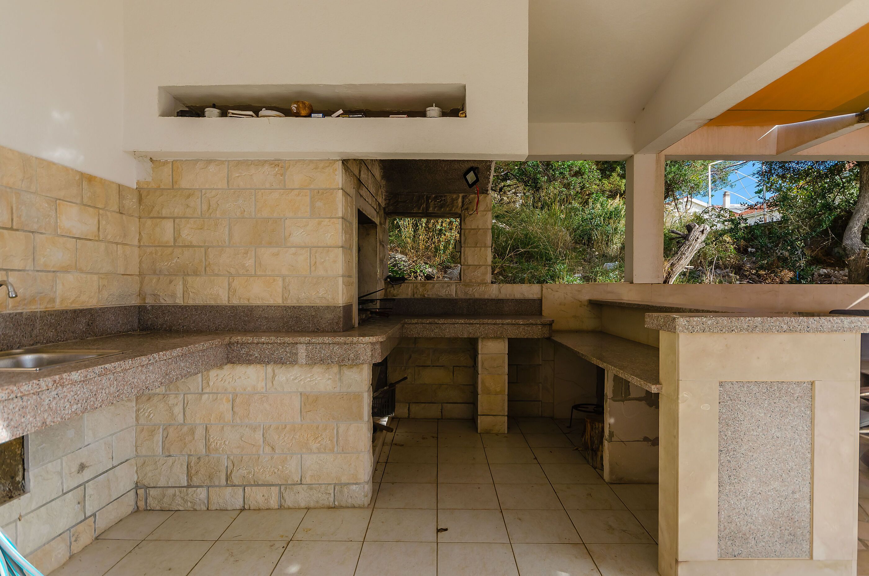 A kitchen with stone countertops, a built-in oven, and a window overlooking greenery.