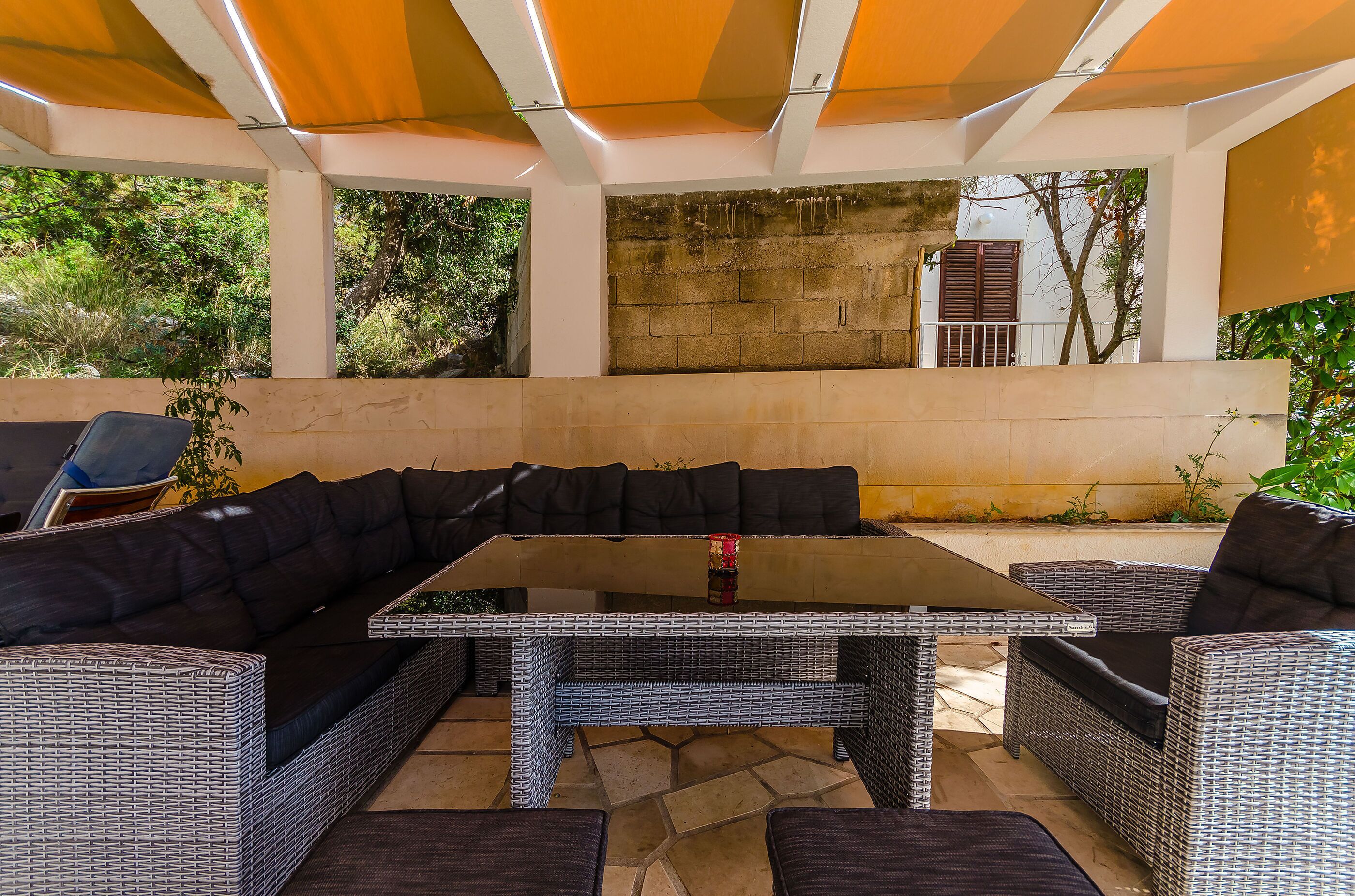 Ein Patio mit Sitzgruppe, Korbmöbeln und einem Boden aus Steinplatten.
