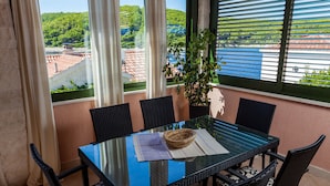 Ein Balkon mit Glastisch, schwarzen Korbstühlen und einer Topfpflanze.
