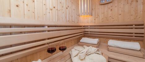 A wooden sauna with benches, towels, and glasses of red wine.