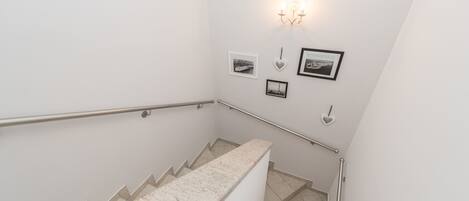 A staircase with a handrail, a wall-mounted light fixture, and several framed pictures.
