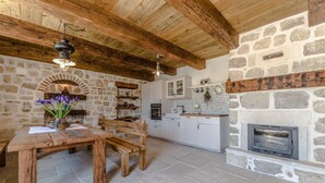 A rustic kitchen with stone walls, wooden beams, and a built-in fireplace. - Villa Lipa (Privlaka)
