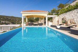 Utendørsbasseng, et evighetsbasseng og solsenger