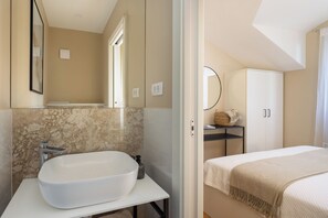 Een moderne badkamer met een groot wit wastafel, een spiegel en een douchegedeelte.