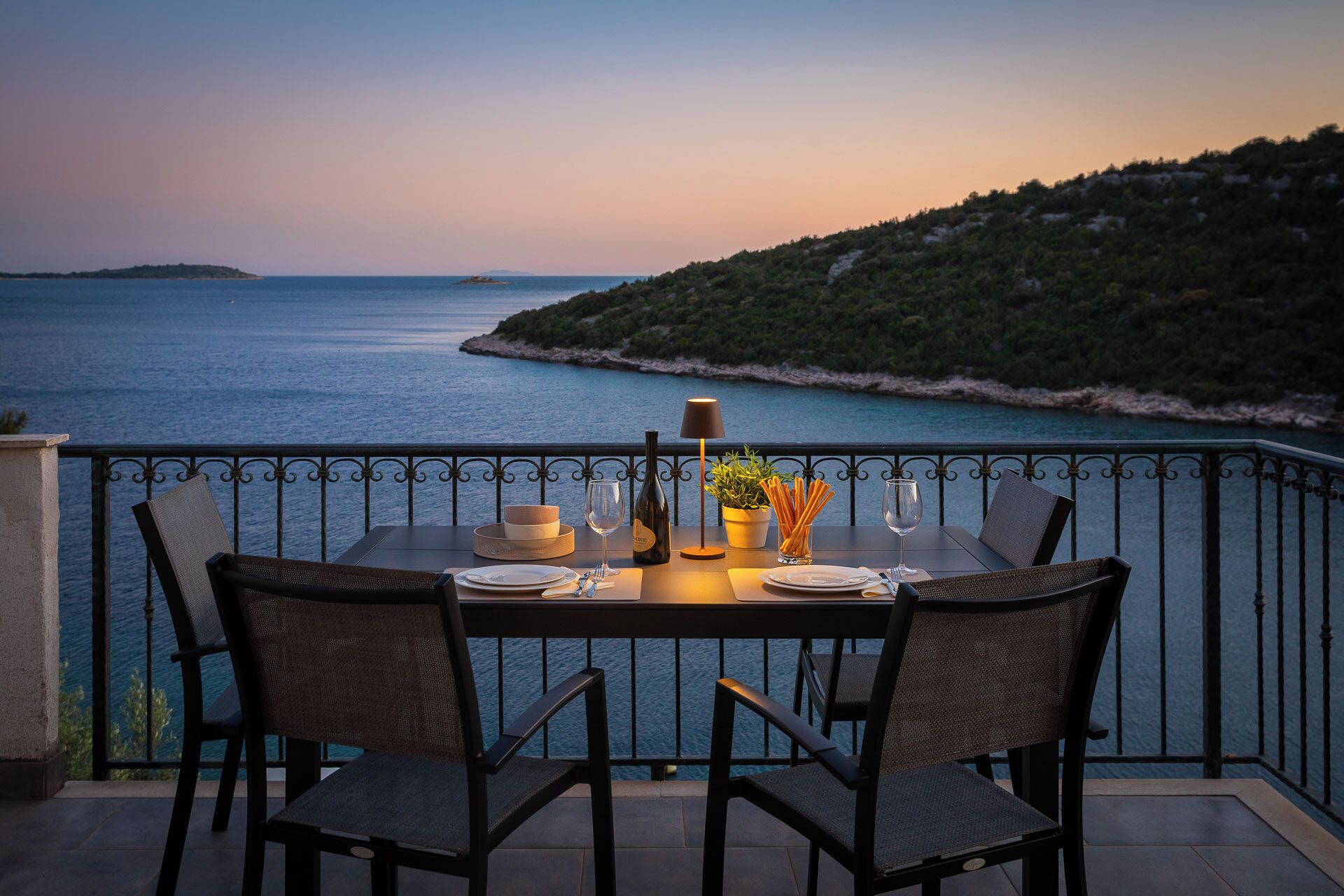 Una mesa para dos con vistas al mar y un paisaje montañoso.