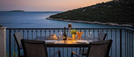 Una mesa para dos con vistas al mar y un paisaje montañoso.