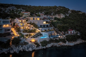 A coastal property with multiple buildings, a swimming pool, and a staircase leading to a terrace.
