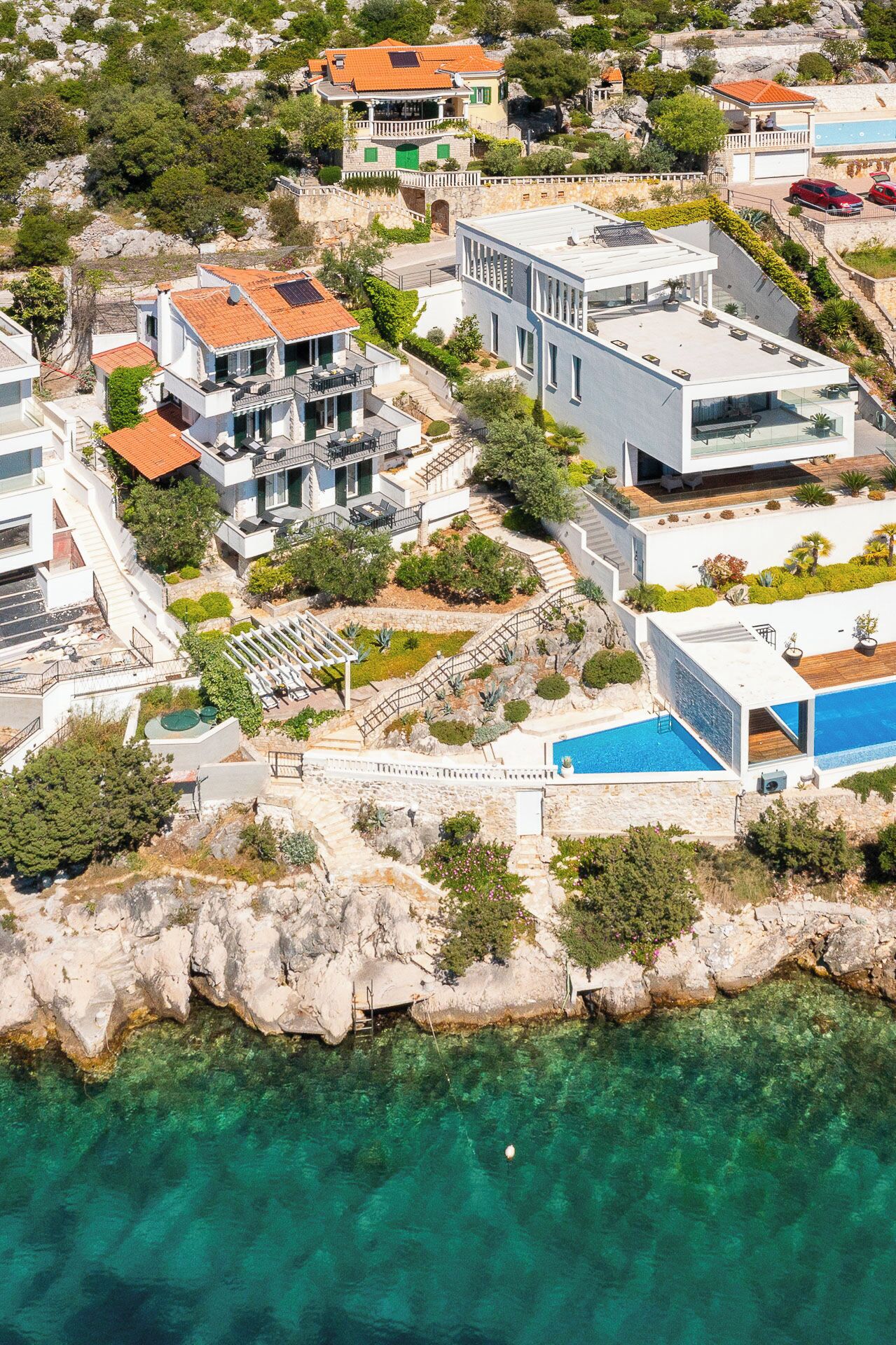 A coastal residential area with modern buildings, a swimming pool, and rocky terrain.