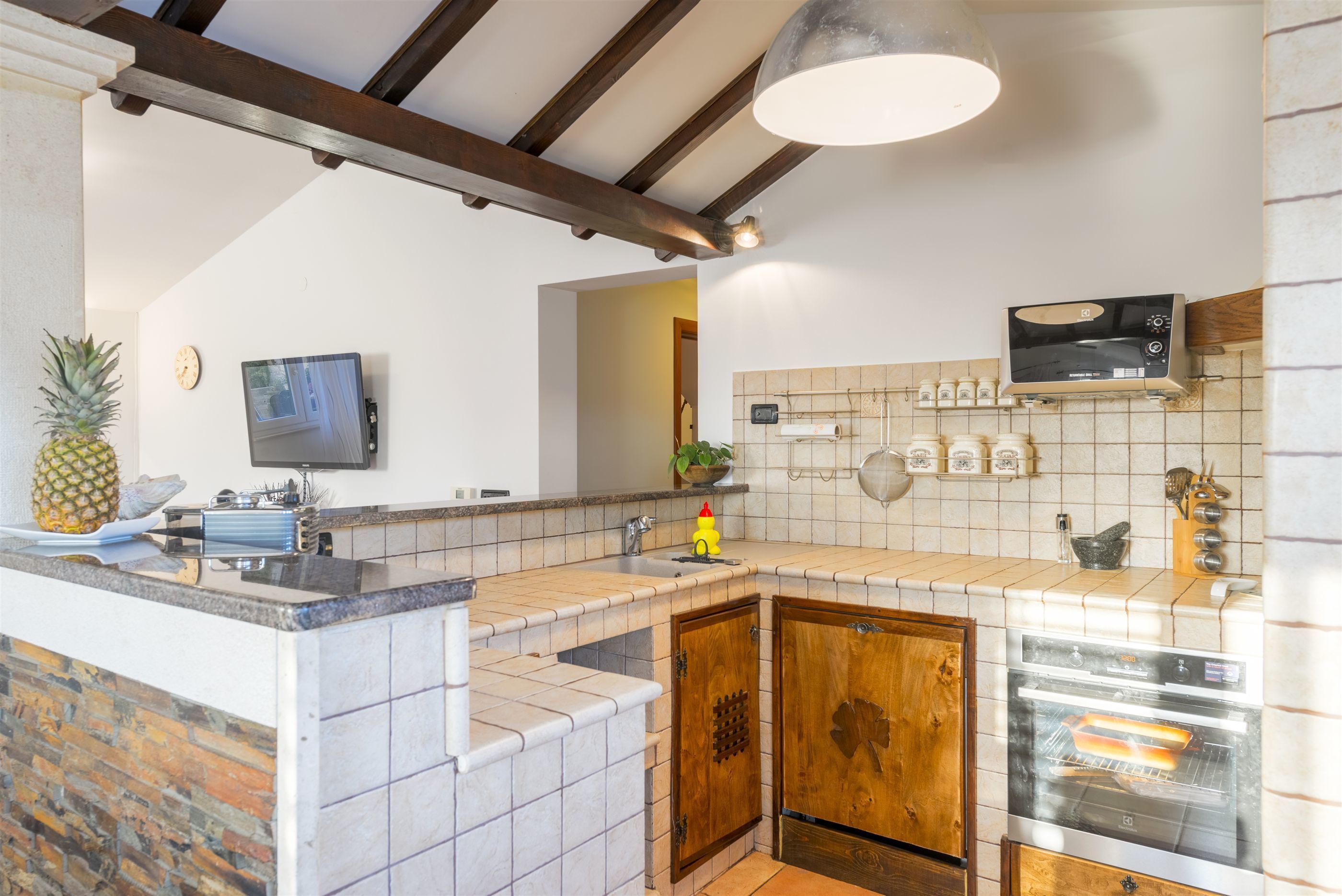 A kitchen with a tiled backsplash, wooden cabinets, a built-in oven, and a microwave.