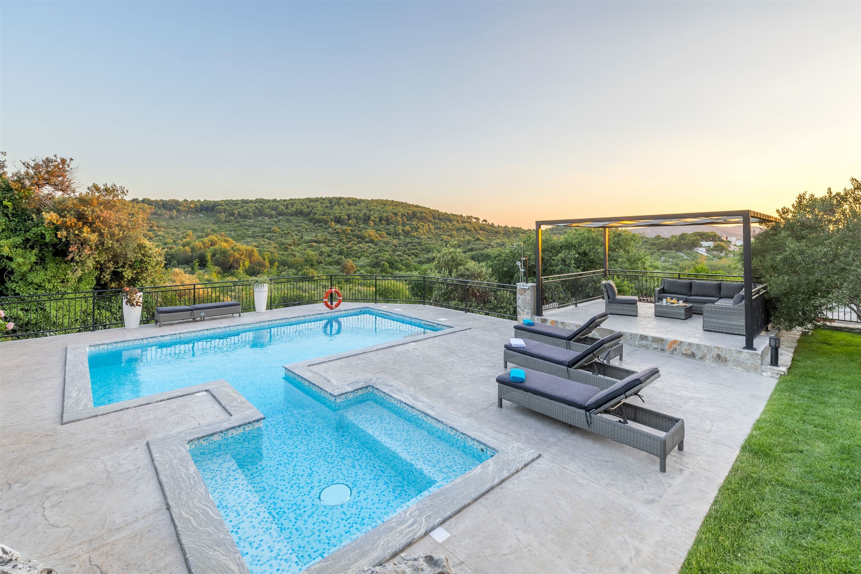 A swimming pool with a deck area, lounge chairs, and a view of a hilly landscape.