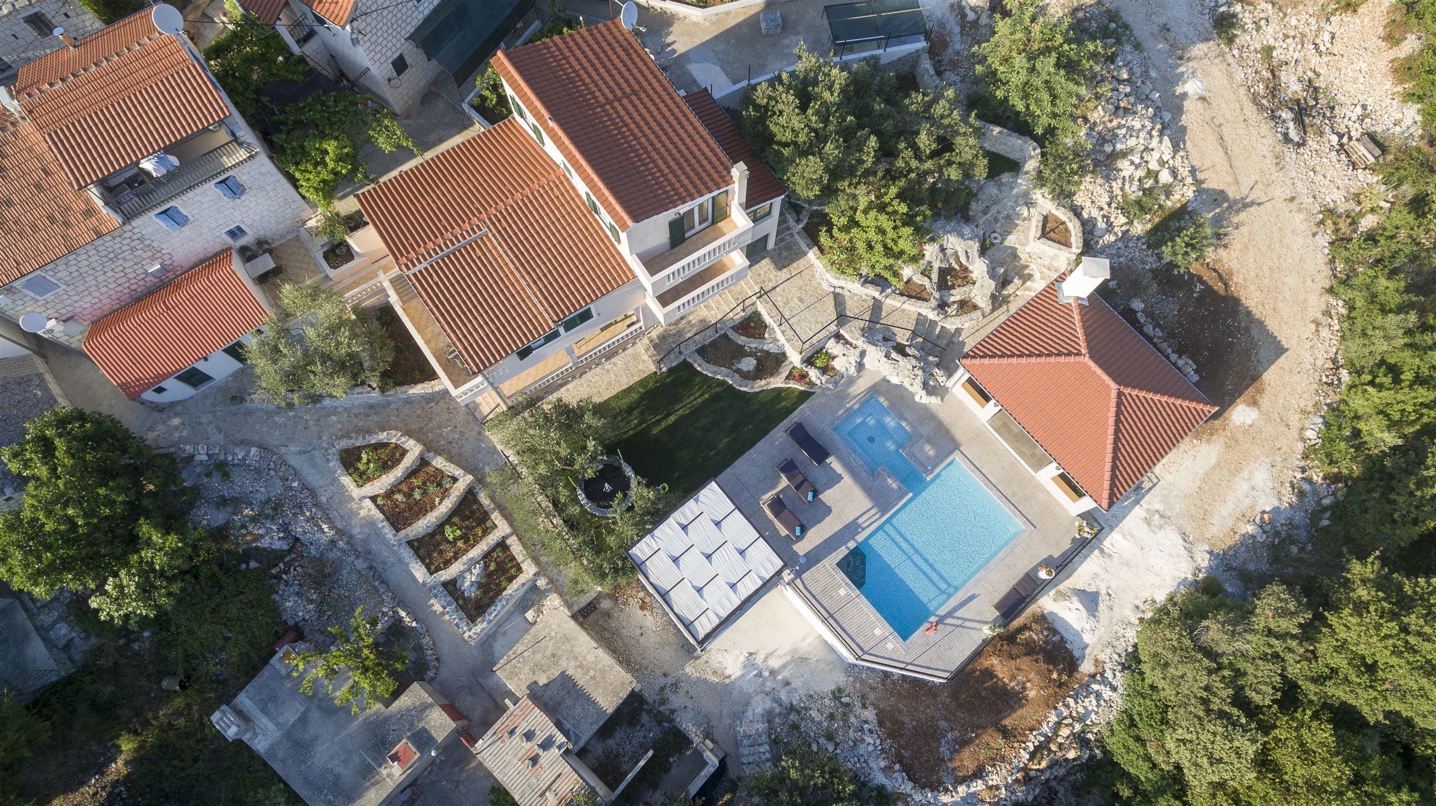 Luchtbeeld van een woonwijk met meerdere huizen, een zwembad en een tuin.
