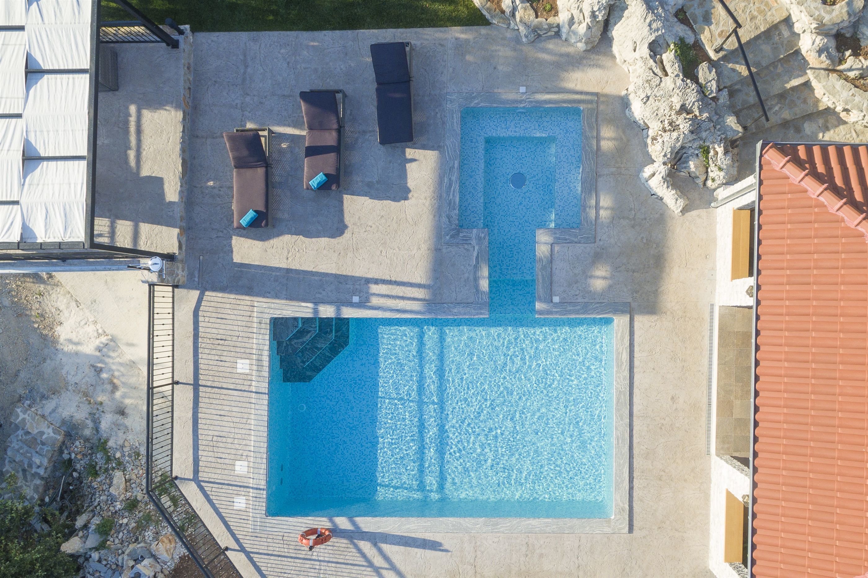 An aerial view of a swimming pool with lounge chairs and a lifeguard chair.