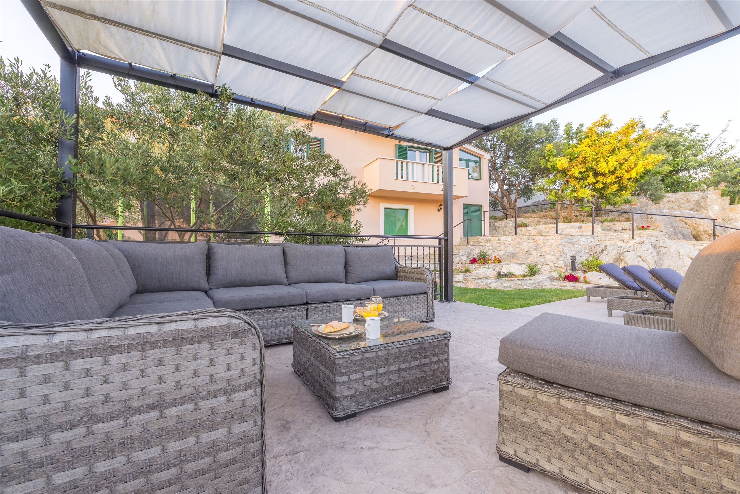 An outdoor seating area with wicker furniture, a glass-top coffee table, and a covered patio.