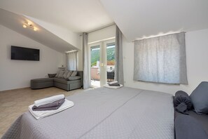 A modern bedroom with a large bed, a sofa, and a TV. - Villa Ruza (Tribalj)
