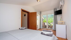 Un dormitorio con cama, escritorio y televisión, y vista al exterior.
