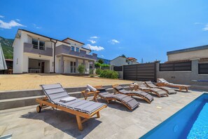 A poolside area with sun loungers and a swimming pool. - Villa Ruza (Tribalj)