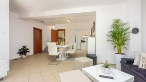 Una sala de estar moderna con comedor, un sofá, una mesa de centro y una planta en maceta.