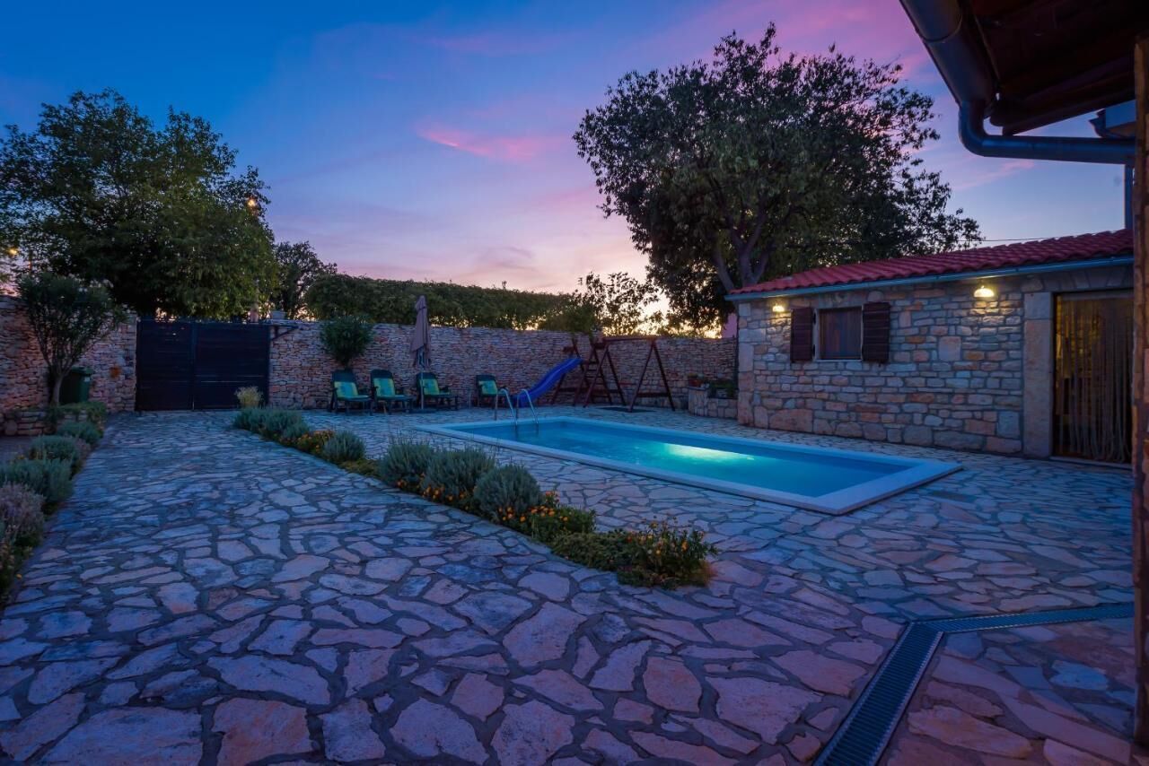 Un patio de piedra con piscina, mobiliario exterior y un edificio de piedra.