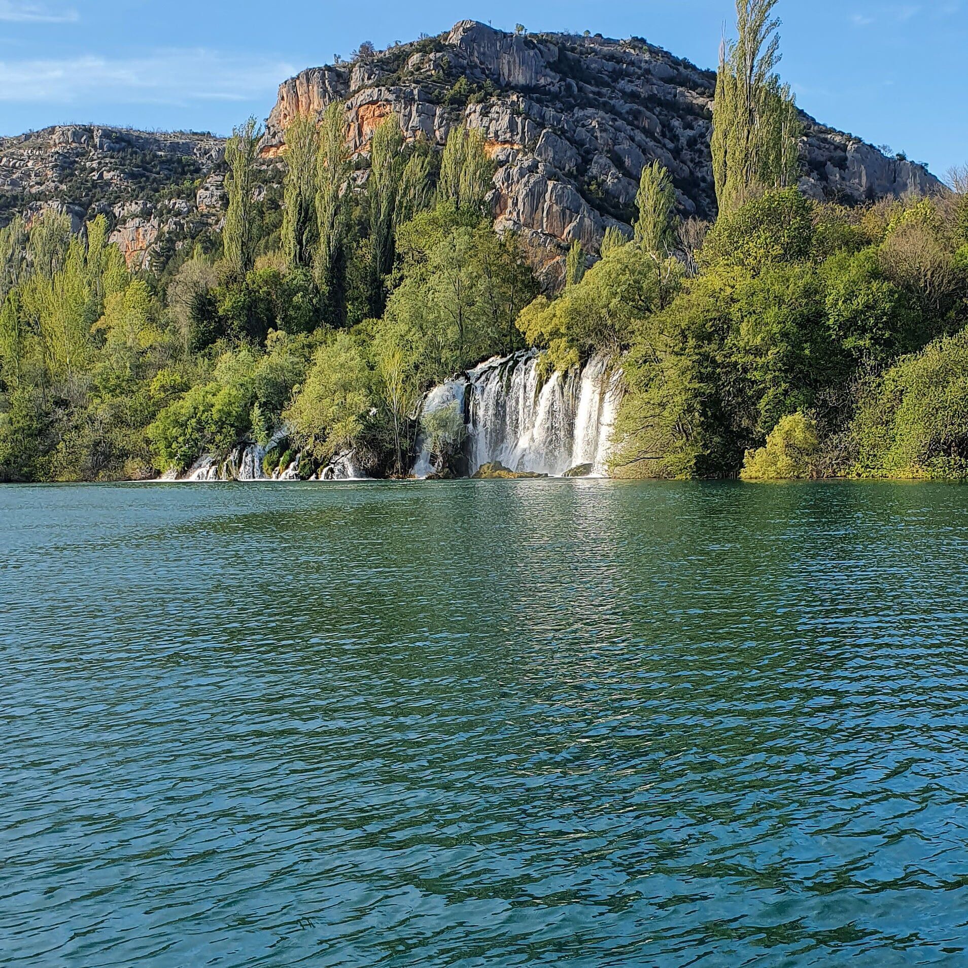 A lake with a waterfall and rocky cliffs.
