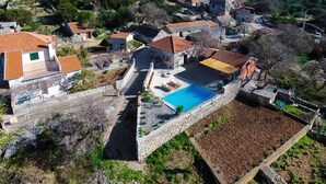 Vista aérea de una zona residencial con edificios de piedra, una piscina y vegetación circundante.